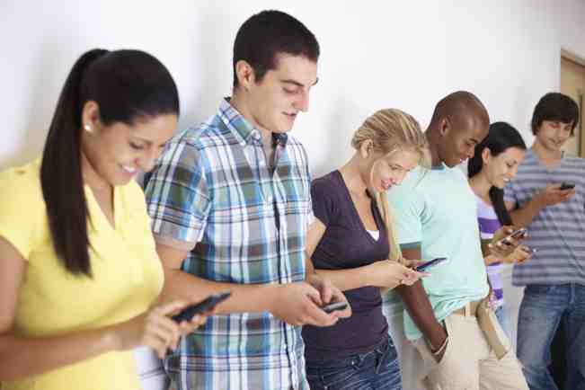 Students texting copyright PixDeluxe iStock_000014390567 Portrait of a college students reading text message on mobile while standing in a row, copyright PixDeluxe iStock_000014390567